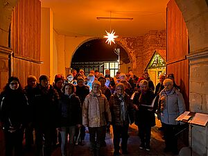 Der Kirchenchor St. Cäcilia Birkungen im Advent unter dem Torbogen des Pfarrhauses. Beleuchtet wird die Toreinfahrt von einem Stern über dem Chor.
